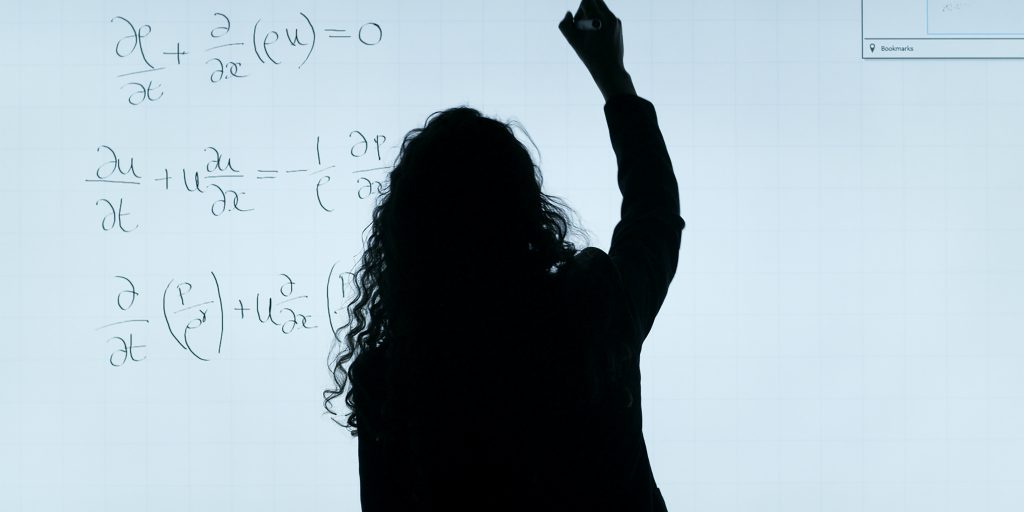 a imagem, utilizada para representar a importância da matemática para a programação, retrata uma mulher resolvendo cálculos matemáticos