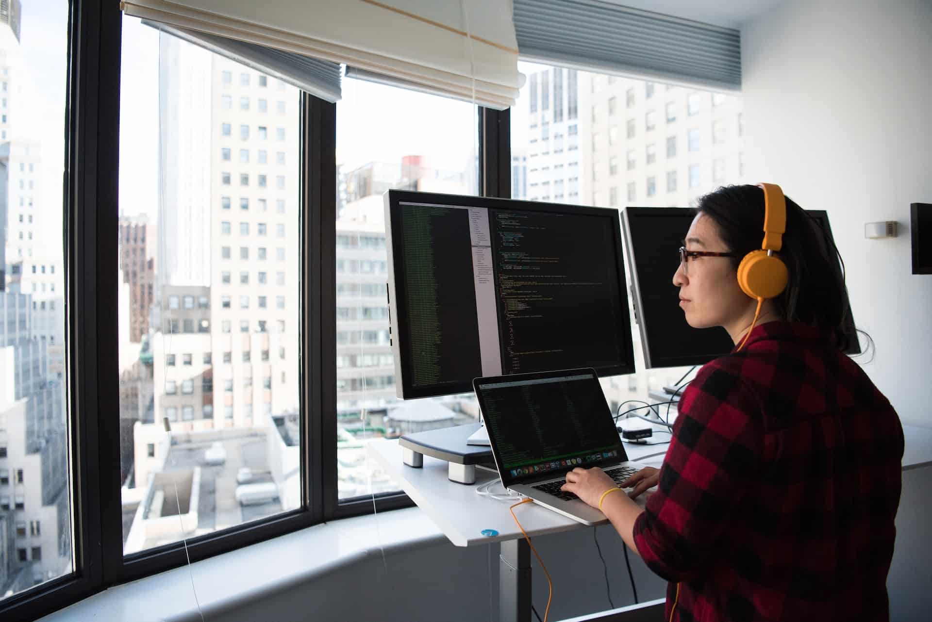 A imagem mostra uma mulher com características orientais sentada à frente de um computador atuando como desenvolvedora back-end node.js