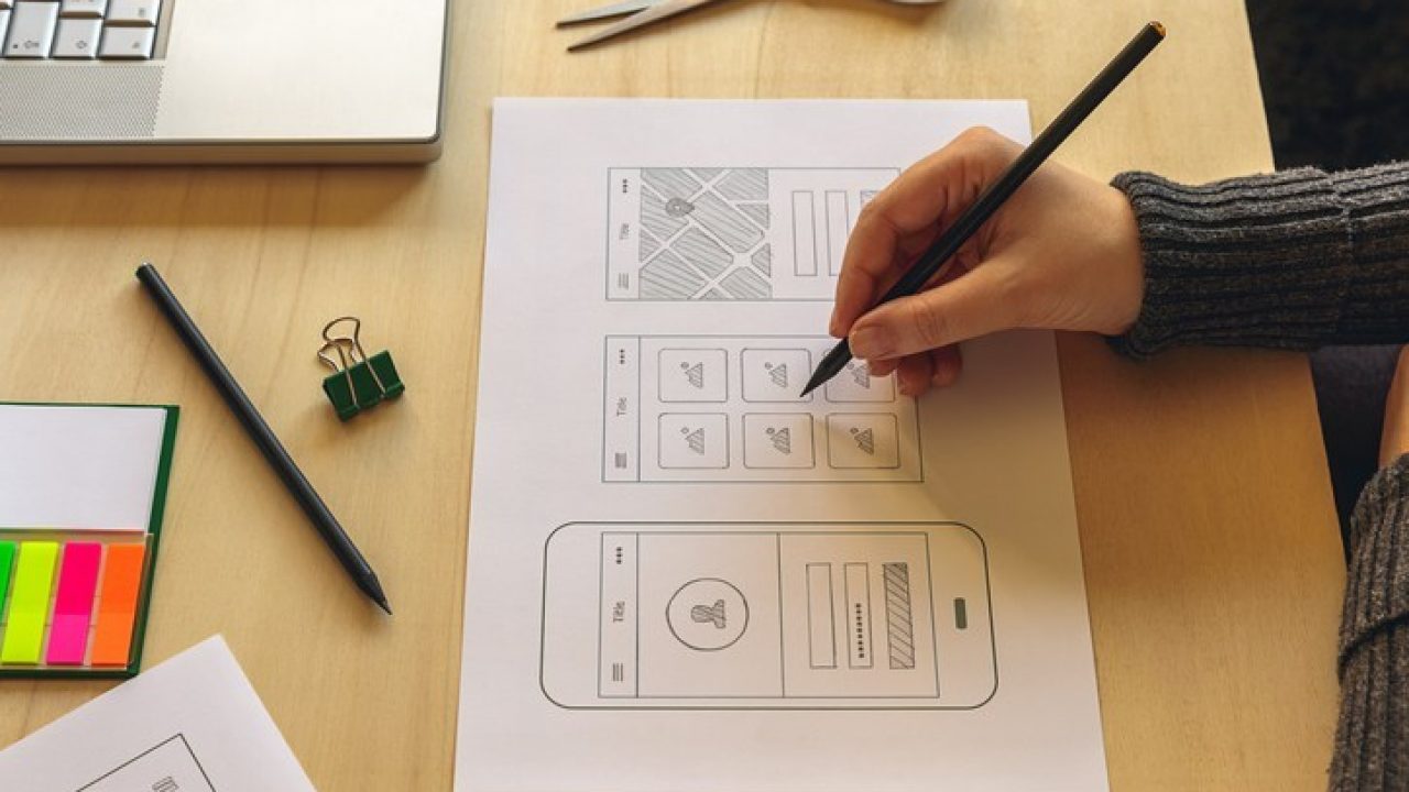 Designer wireframing a mobile App on wooden desk