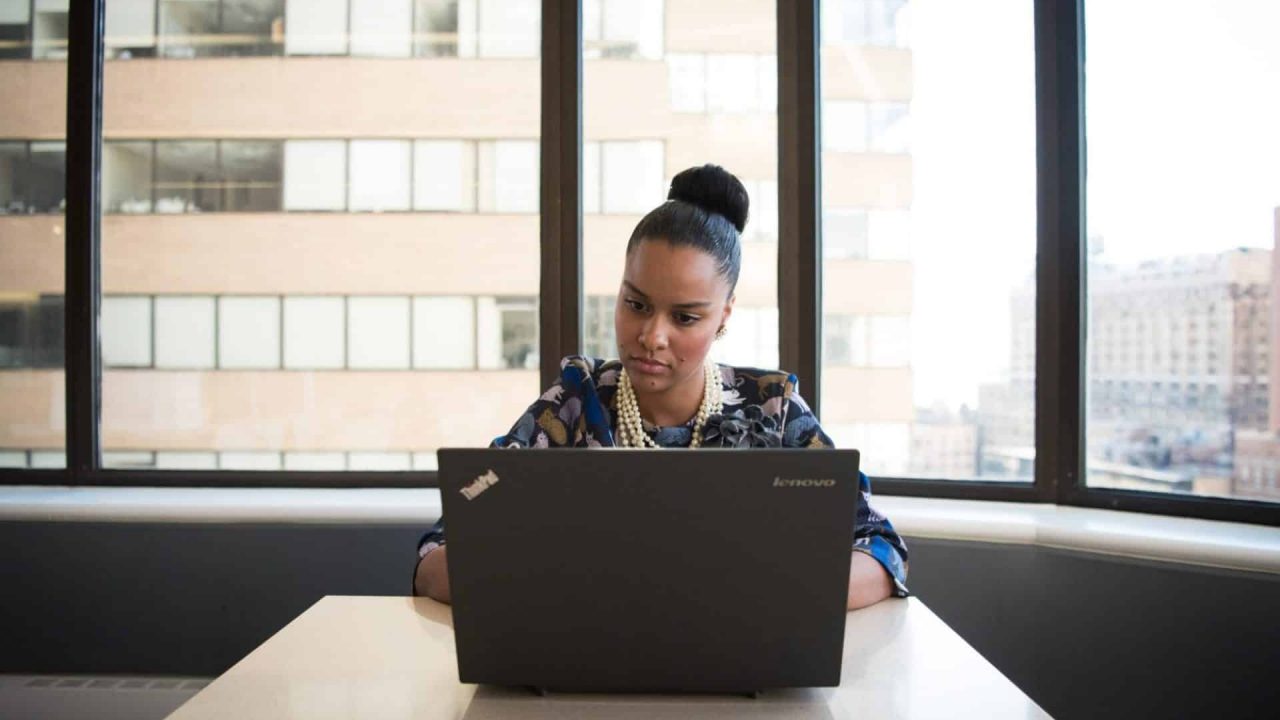 a imagem mostra uma mulher negra, setada à frente de um computador, representando um tech recruiter
